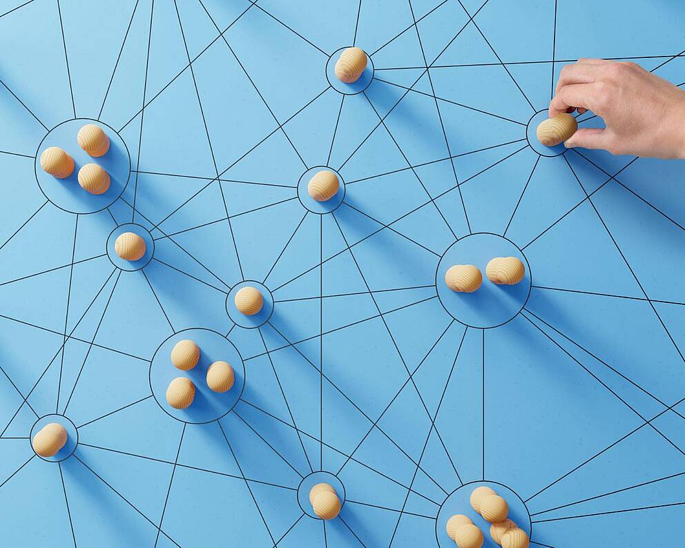 Symbolbild mit Linienstrukturen und Holzobjekten, von denen eines wie bei einem Strategiespiel